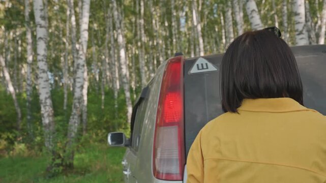 Preparing for overnight forest adventure. Caucasian woman arranging supplies in woodland setting. Woman from Caucasia organizes her camping essentials in quiet birch forest preparing for night