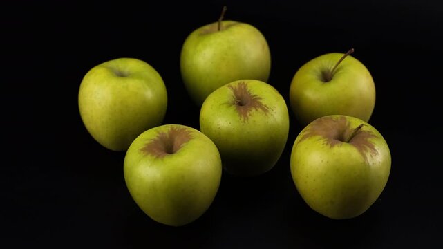 Six fresh green apples in a smooth motorized camera slider shot on a black background