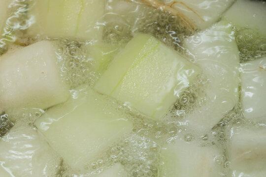 Winter melon boiling in a pot of hot water, bubbling vigorously with steam, showing cooking process