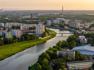 Malownicza panorama Opola z lotu ptaka nad rzeką Odrą o zachodzie słońca. Widok na architekturę miasta, mosty i zieleń w złotej godzinie. Krajobraz miejski Polski w ciepłym świetle wieczornym. © Henryk Niestrój