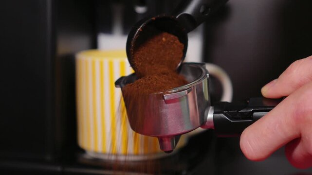Close-up of a barista tempering freshly ground coffee with a tempera in a coffee shop. The process of making espresso. Footage of barista tamping coffee in pitcher of a barista crafting an Americano. 
