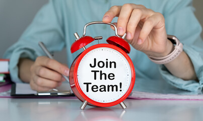 Close-up of a person holding a red alarm clock with Join The Team text, emphasizing dynamic hiring...