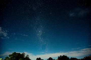 Starry Night Sky Above Treeline, Faint Milky Way Band Arcing Across Deep Blue Gradient, Silhouetted Trees © 21AERIALS