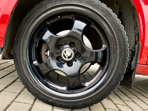 Close-up of a red Skoda Fabia wheel featuring glossy black alloy rims with five spokes. The Skoda logo is prominently displayed at the center of the hubcap. The tire appears to be a summer variety