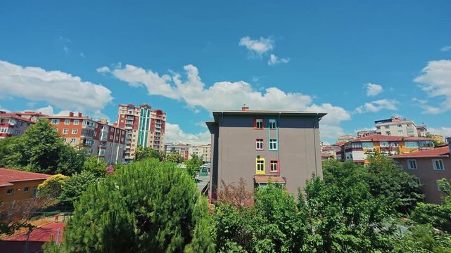 Time lapse of clouds drifting over colorful residential buildings and lush green treetops on Istanbul's Asian side on a sunny summer day