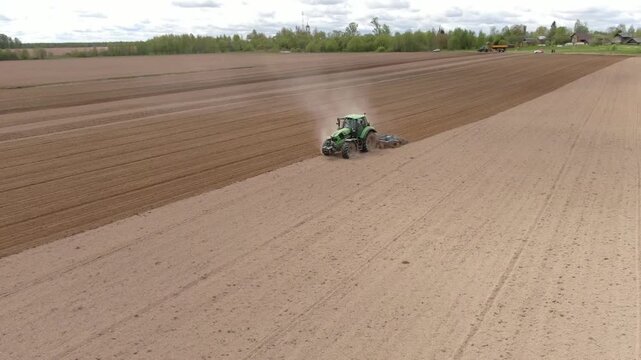 Drone descending and circling tractor on potato field