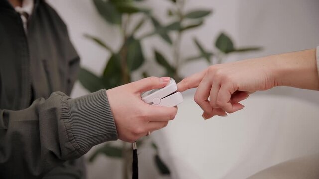 Doctor preparing to use pulse oximeter on patient's finger, measuring oxygen saturation and heart rate. Close up
