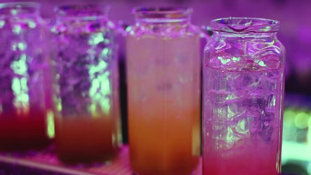 Barman mixing and pouring drinks and beverages, beautiful row line of different coloured lemonades in a jar, liquor alcohol cocktails on a party in bar, catering banquet on event, mocktails in a jug 