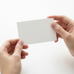 Obraz premium Two hands exchanging a blank business card against a plain background