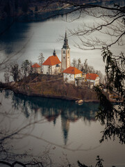 Fototapeta premium Lake Bled Island Through Branches, Slovenia, Winter Scene with Natural Framing