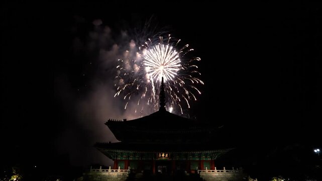 Fireworks exploding over traditional building at night.