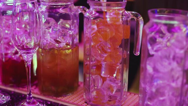Barman mixing and pouring drinks and beverages, beautiful row line of different coloured lemonades in a jar, liquor alcohol cocktails on a party in bar, catering banquet on event, mocktails in a jug 