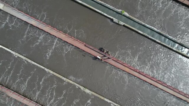 Wastewater treatment aeration basins with bubbling influent at industrial plant lateral pan, Aerial top view.
