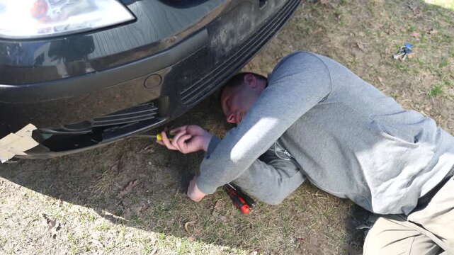 close up of the mechanic's hands, who removes the bumper of the car, he repairs the car.