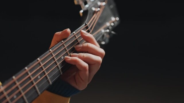 Closeup acoustic guitar hand forming open chords with slow deliberate strumming, knit sweater sleeve visible, warm amber light, intimate rehearsal vibe, musician refining rhythm and tone