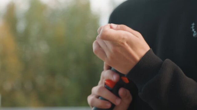 Hands inspect equipment. Person secures drill by railing. Focused person conducts final safety inspection carefully. Calm worker tests and secures drill near trees during evening hours