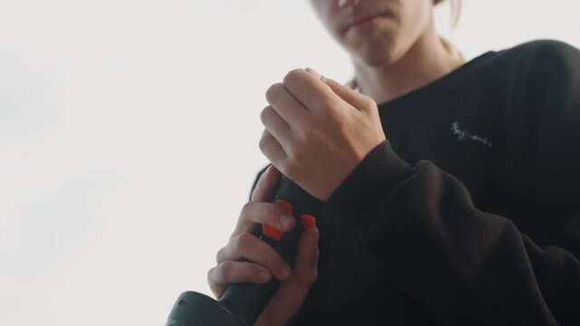 Person inspecting cordless drill outdoors, midshot showing trigger and bit, thoughtful handling, stepwise adjustment, battery check, soft backlight, practical tutorial vibe, precise finger work