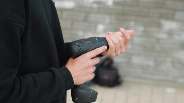 Closeup hands swapping drill bit with careful inspection, tactile adjustments and steady wrist control, focused maintenance check in outdoor workshop, final safety verification and fine calibration