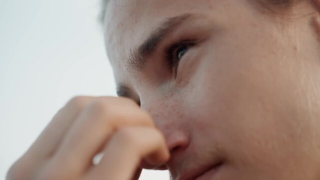 Displeased man reacts poorly to foul scent. Individual shows disgust after perceiving unpleasant outside aroma. Young observer grimaces upon sensing offensive and unwelcome outdoor smell