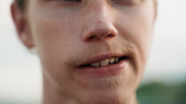 Closeup white male speaking smile teeth visible, confident delivery, warm expression and stubbled chin, outdoor blurred background, conversational energy, rooftop monologue, candid communication