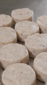 Vertical video. Cook lifts metal forming ring releasing soft rounded patty onto cold polished surface. Smooth careful gesture shapes tidy line of fragrant mixed minced mass ready for freezing
