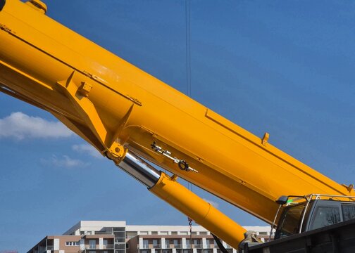 Side detail shot of a 450-ton mobile crane featuring the operator cabin and a massive hydraulic cylinder under the chassis.