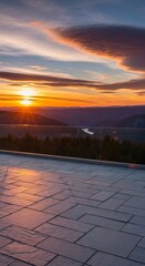 Fototapeta premium Balcony view of a breathtaking sunset over a vast valley with a winding river and distant mountains, reflecting golden light on the patio.