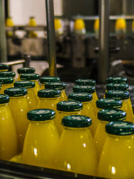 Industrial beverage production line in a factory, showing plastic bottles filled with juice moving along an automated conveyor system. The image highlights bottling processes, quality control, and lar