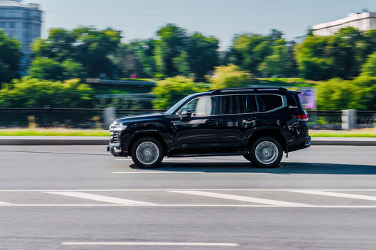 Toyota Land Cruiser 300 rides on the city highway. Black premium SUV on the city street in motion.