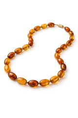 Obraz premium A necklace made of amber beads is placed on a white surface. The necklace shows various shades of amber, highlighting its design and craftsmanship