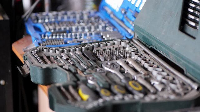 A close-up video shows two open professional tool kits filled with sockets, bits, and ratchets, as the camera smoothly moves forward highlighting the organized layout and metal details in a workshop 