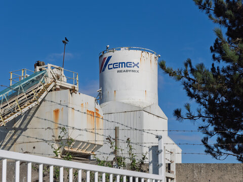Industrial cement plant Cemex in Salford Manchester with machinery under a clear blue sky.