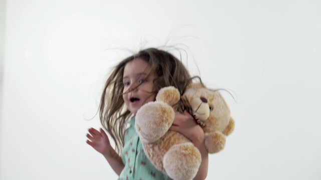 Beautiful little girl in a bright dress jumping with a soft toy in her hands. Sumer Slow Motion