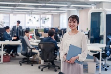 Fototapeta premium オフィスで笑顔で書類を持つ女性