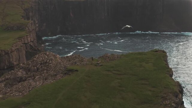 Cinematic aerial view of Faroe Islands, showcasing rugged cliffs, lush green slopes, and misty Nordic seascape