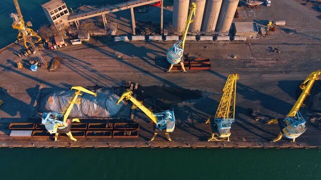 Top view of yellow portal cranes at port. Aerial shot of industrial cranes loading cargo into railway wagons.