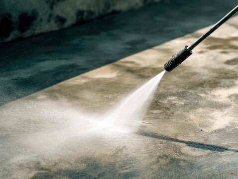 Power washing a concrete surface to remove dirt and grime with a high-pressure water spray for outdoor cleaning and maintenance purposes