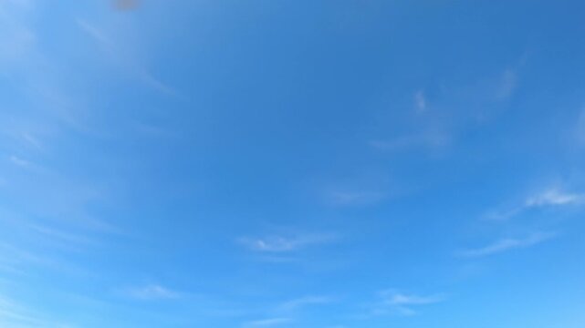 Ultra-wide drone video of an immense, pristine light blue sky with delicate, wispy white cirrus clouds, bathed in clean natural daylight. concept of limitless possibilities