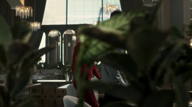 Guy and a girl dressed nicely came to a romantic date in a restaurant with a lot of indoor plants
