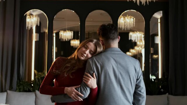Young girl who loves hugs her boyfriend at her high school graduation and rests her head on his shoulder