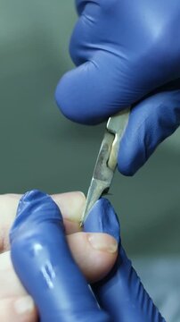 Man uses bronze nail clippers on little toe in low light with dark background. High quality 4k footage