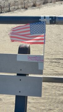 Small American flag on a windy day attached to a rail at the beach.