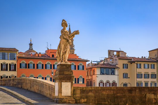 Marble statue of Summer by Giovanni Caccini stands on the Santa Trinita bridge, overlooking the historic Arno riverfront in Florence, Italy