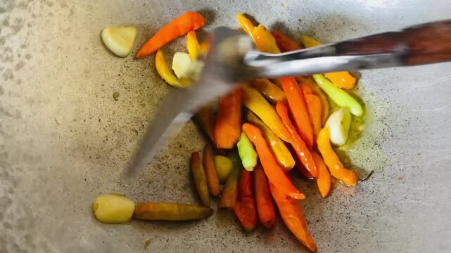 Chili and garlic sizzling in a pan with a small amount of oil, capturing the start of sambal making, rich aroma, vibrant color, and authentic home cooking moment.