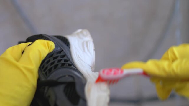 Hands in Yellow Gloves Cleaning Sneaker Sole with Toothbrush, Shoe Maintenance Life Hack and Restoration, Domestic Cleaning and Footwear Care Detail