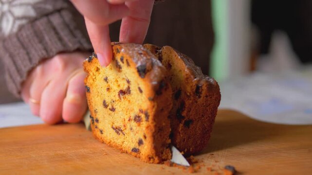 Hands Slicing Fresh Fruitcake with Raisins on Wooden Board, Traditional Home Baking and Culinary Food Preparation, Golden Brown Loaf Cake Texture