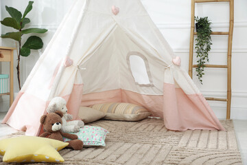 Toy wigwam with pillows and floral decor in room, closeup © New Africa