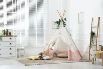 Toy wigwam with pillows, furniture and floral decor in room © New Africa