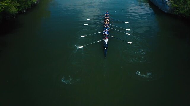 Rowing team athletes training with their sculling boat on a river during an early morning practice