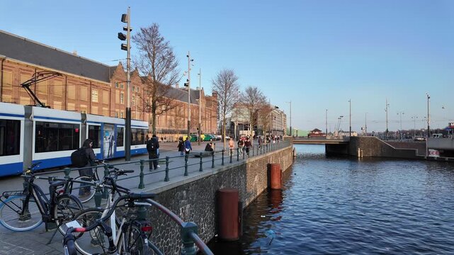 A view of a the shore of a dutch canal in the city centre of Amsterdam with the Kamper bridge visible.